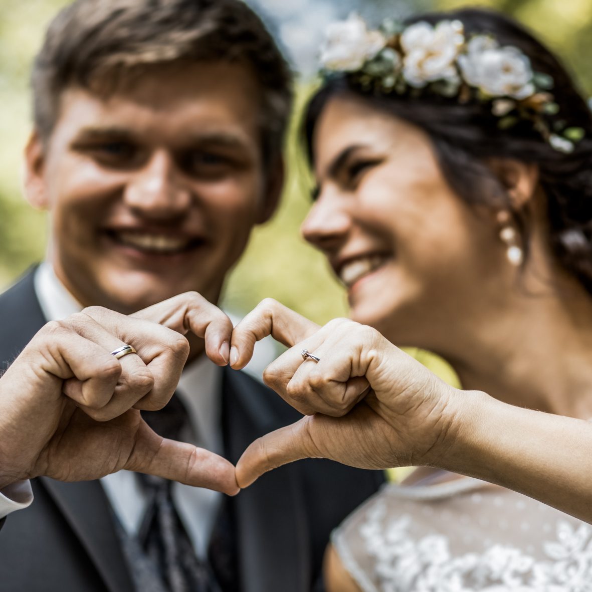 Brautpaar formt Herz mit den Händen Braut und Bräutigam formen mit ihren Händen ein Herz und lächeln sich bei der Hochzeit an.