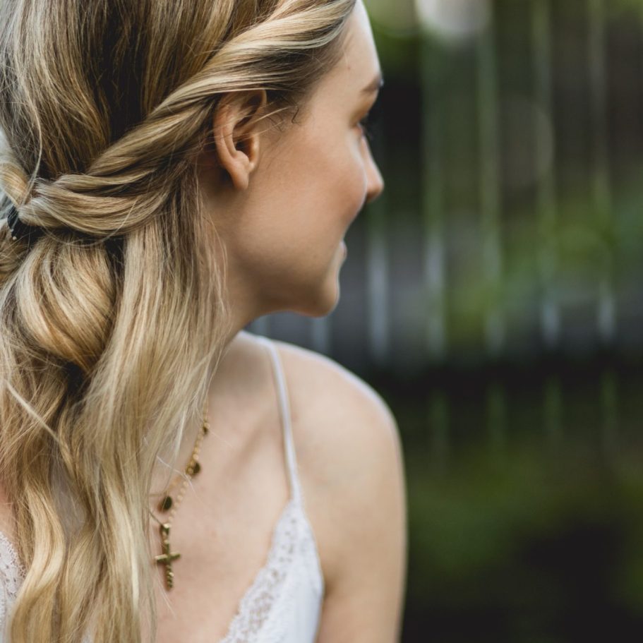 Portrait einer Frau im Profil im Freien Seitliches Portrait einer jungen Frau mit geflochtenem Haar vor grünem, unscharfem Hintergrund.
