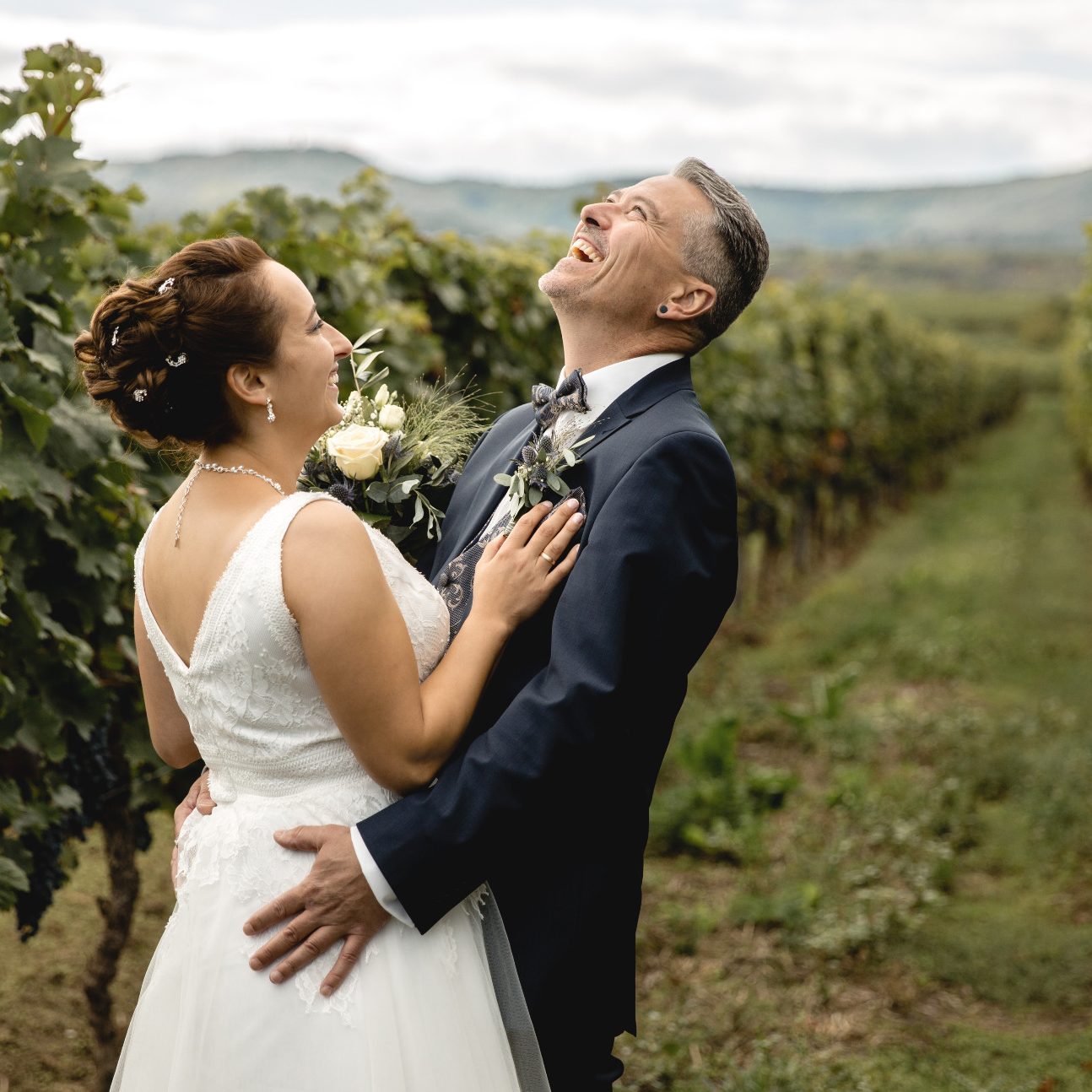 Lachendes Brautpaar im Weinberg Fröhliches Brautpaar zwischen Weinreben bei Hochzeitsshooting.
