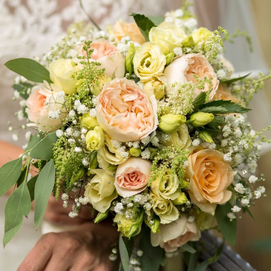 Brautstrauß mit Rosen und Eukalyptus Hochzeitsstrauß mit hellen Rosen, Schleierkraut und grünem Blattwerk in Nahaufnahme.