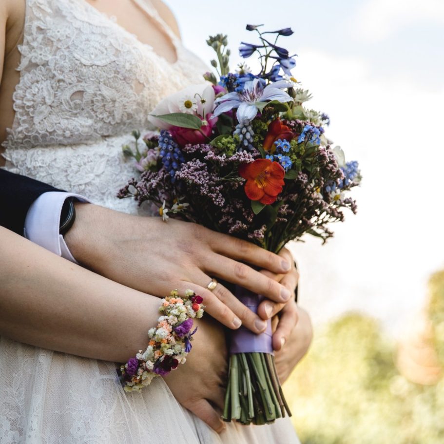 Brautstrauß in Nahaufnahme Nahaufnahme eines bunten Brautstraußes vor dem Hochzeitskleid der Braut.