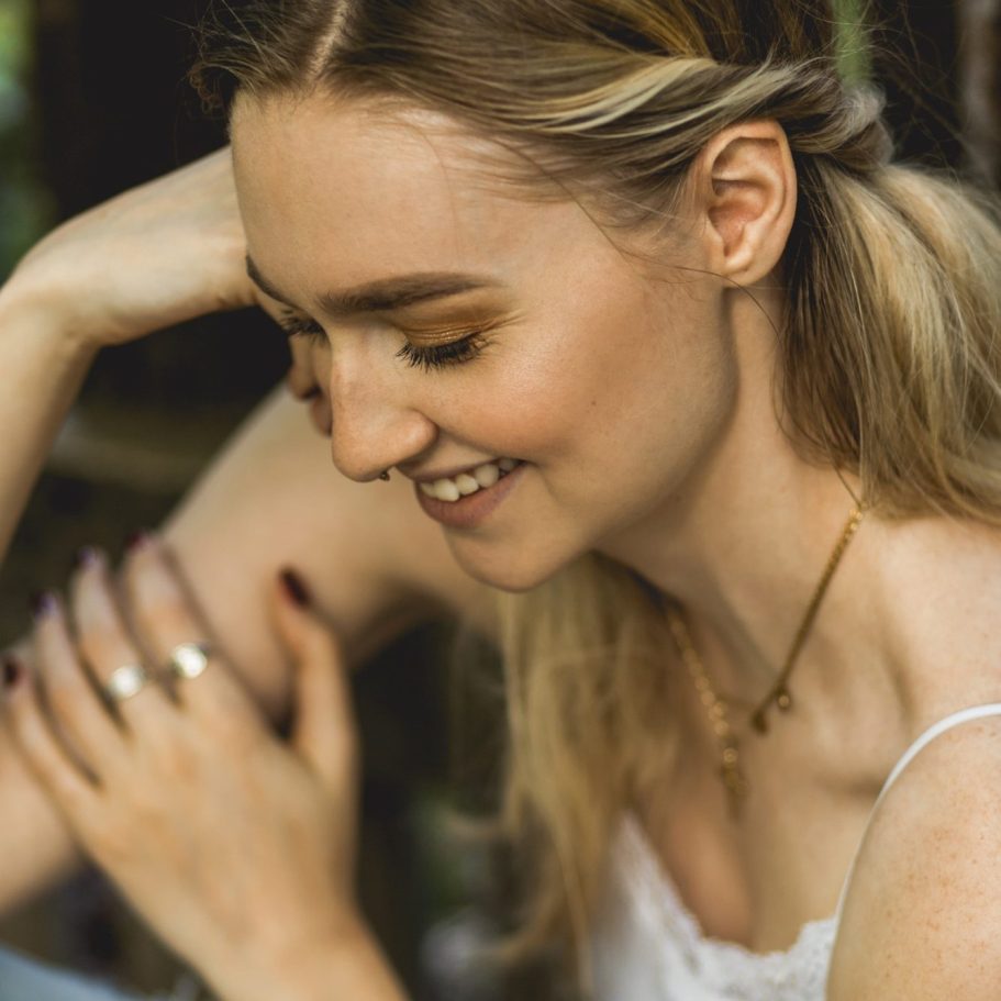 Lächelnde Frau im Outdoor-Portrait Junge Frau mit gesenktem Blick und leichtem Lächeln in natürlicher Umgebung bei weichem Tageslicht.