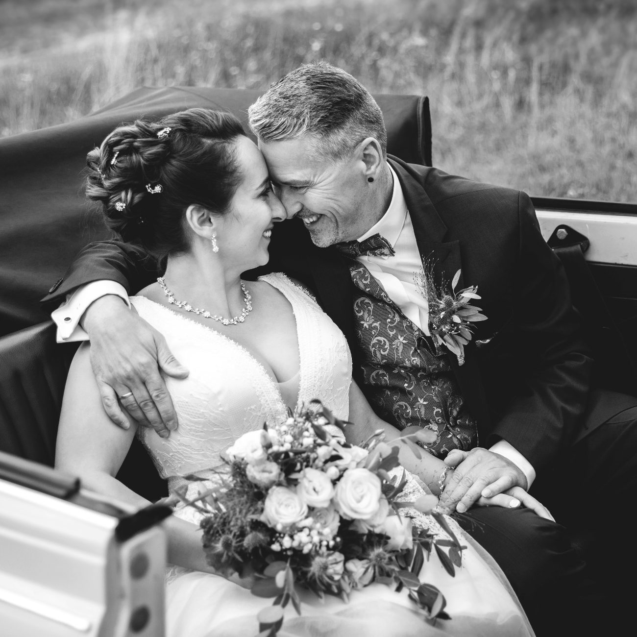 Brautpaar im Hochzeitsauto Intimes Hochzeitsfoto eines Brautpaares im Fahrzeug, fotografiert in Schwarzweiß.
